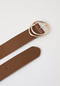 Bruine leren riem met een gouden ronde gesp met twee ringen, een gladde textuur en keurig gestikte randen langs de lengte.