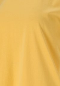 Gul bomuldsstof med en glat tekstur, der har blød fald og minimal stræk. Viser en jævn farve uden mønstre eller accenter.