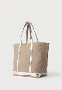 Μεγάλη μπεζ τσάντα χειρός από καμβά με ασημί μεταλλικές λεπτομέρειες στα χερούλια και στη βάση, με δύο ανθεκτικούς ιμάντες και απαλό, υφασμάτινο υλικό.