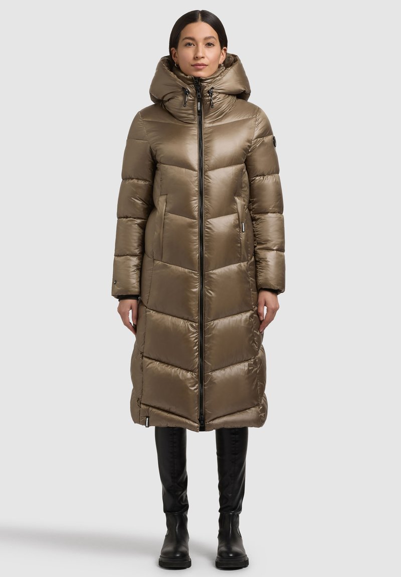 Lang, hætteklædt dynejakke i en varm beige farve med quiltede paneler, en lynlås foran og sidelommer. Glat, skinnende tekstur.