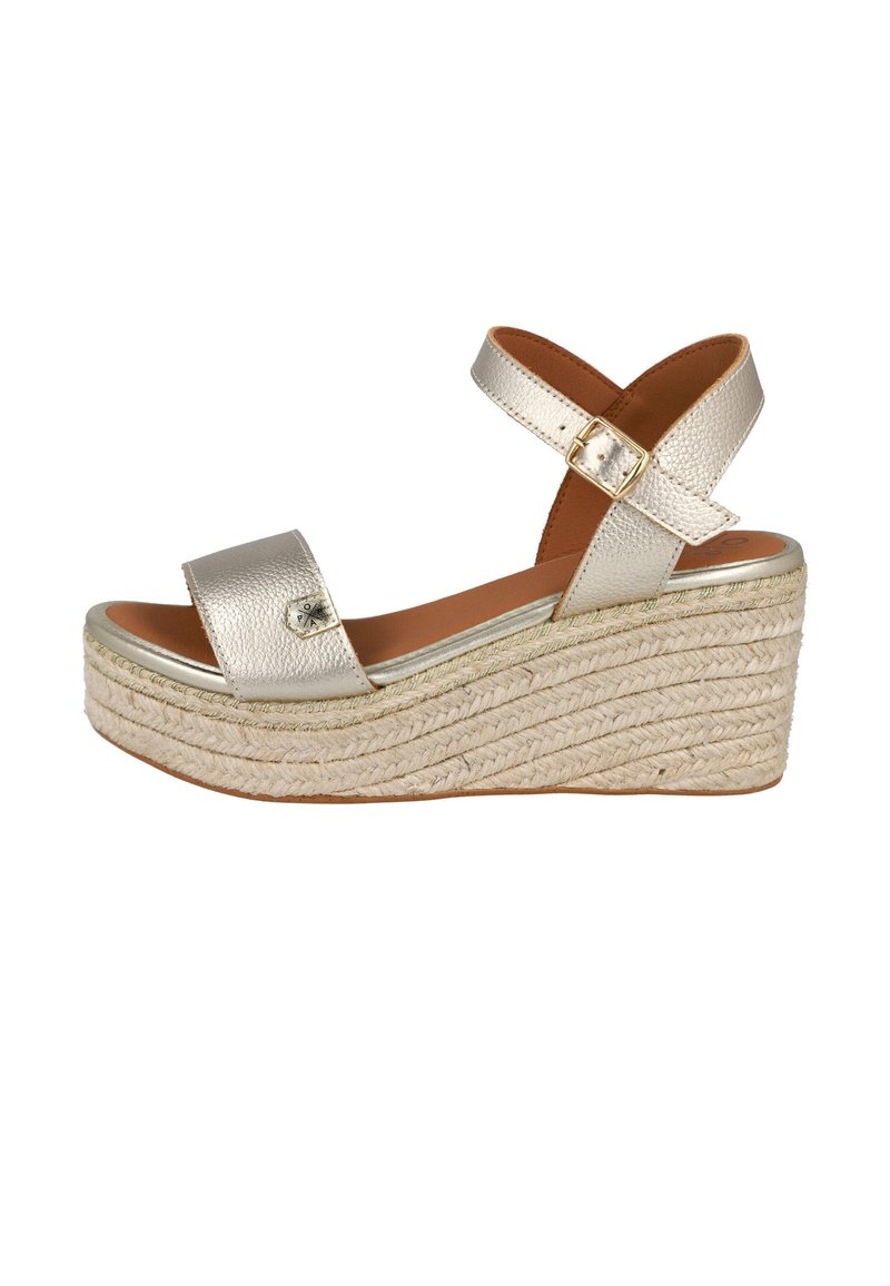 Sandalia plataforma metálica dorada con dos correas anchas, una correa ajustable en el tobillo y un tacón cuña envuelto en yute. Textura suave.