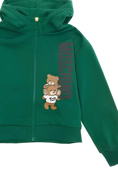 Felpa verde con zip, decorata da una grafica di un orsetto, uno dei quali indossa una maglietta con la scritta "TOY", e "MOSCHINO" stampato verticalmente in lettere scure.
