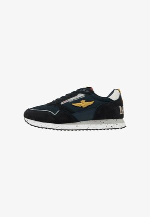 Black and navy sneaker with white speckled sole, gold winged emblem on side, and white heel accent with stitched logo detail.