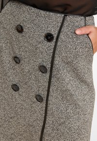 Op maat gemaakte rok in gestructureerde zwart-witte stof, met een dubbelzijdig ontwerp, zwarte knopen en contrasterende piping langs de zijkant.