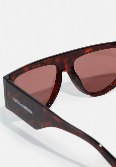 Red tortoiseshell sunglasses with angular shape, brown lenses, and a matte finish. Features logo on the temple.