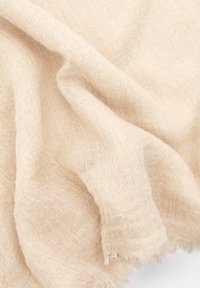 Vaaleanbeige pellavakangas, jossa on pehmeä, molemmat pinnat, joissa on rispaantuneet reunat ja lempeät taitteet. Kankaalla on luonnollinen ja ilmava ulkonäkö.