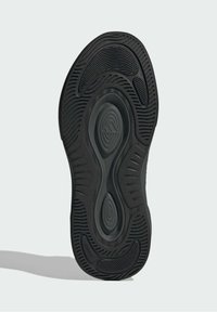 Čierna gumená podrážka topánky s textúrovaným vzorom so zrezanými a kruhovými detailmi. Hladká stredná časť a vyrazené logo.