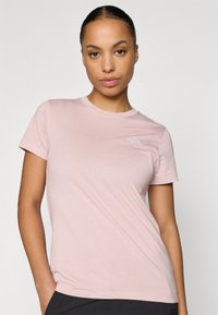 Ανοιχτό ροζ κοντομάνικη μπλούζα από μαλακό ύφασμα με μικρό λογότυπο στην αριστερή πλευρά του στήθους. Κλασικός σχεδιασμός με στρογγυλή λαιμόκοψη.