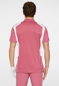 Kortärmad pikétröja i rosa med vita sidopaneler; tillverkad av smidigt, lätt material; har en klassisk krage och en slank passform.