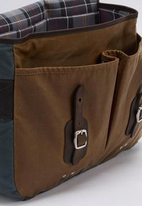 Καφέ καμβάς τσάντα με δερμάτινες λεπτομέρειες, που διαθέτει αρκετές μπροστινές τσέπες, καρό επένδυση και ασημένιες λεπτομ�έρειες.