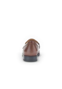 Bruine leren herenschoenen met een ronde neus, een vlakke zwarte zool en minimale stikseldetails. De achterkant heeft een subtiele hak en een gladde afwerking.