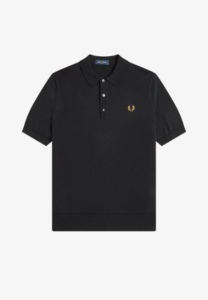 Camiseta polo negra de manga corta con cuello, tres botones y pequeño logotipo de corona de laurel amarilla en el lado izquierdo del pecho.