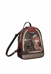 Mochila de lona marrón con acentos rojos. Presenta una ilustración decorativa de una niña frente a la Torre Eiffel. Cierres de cremallera.