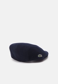 Navy wool beret with a rounded shape, featuring stitched accents and a small embroidered crocodile logo on the side.