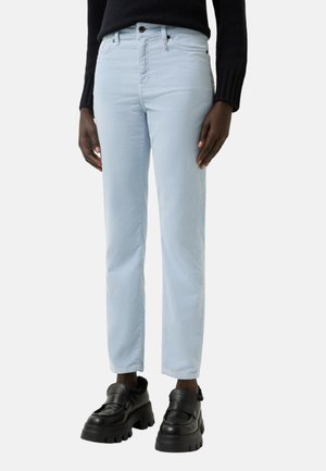 Light blue cotton jeans with a straight fit, five-pocket design, zip fly, and button closure. Paired with chunky black platform shoes.