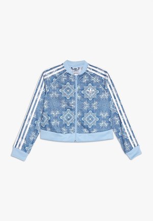 Lysblå zip-up jakke med hvide ornamentale geometriske mønstre, tre hvide striber på ærmerne, ribbede manchetter og krave.