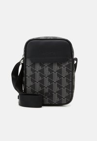 Black crossbody bag with a geometric pattern. Made of textured material, featuring a smooth top panel and adjustable strap.