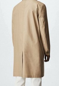 Cappotto lungo beige chiaro con taglio dritto, dotato di uno spacco sul retro e maniche lunghe, realizzato in un tessuto morbido e leggero.