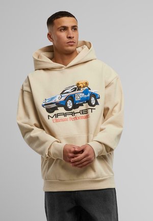 Beige hoodie featuring a blue car graphic with a bear, "MARKET" text, and "Ultimate Performance" in orange. Soft fabric, relaxed fit.