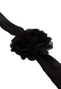 Sort stof hårbånd med et stort, lagdelt blomsterdesign med bløde blade. Båndet er glat og lavet af et gennemsigtigt materiale.
