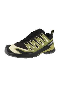Scarpa sportiva nera e verde con una parte superiore texturizzata, rete leggera e suola in gomma dotata di scanalature di trazione prominenti e punta rinforzata.