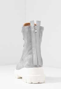 Stivaletto in suede grigio con suola spessa bianca e cerniera sul retro. Caratterizzato da una texture liscia e un design arrotondato.