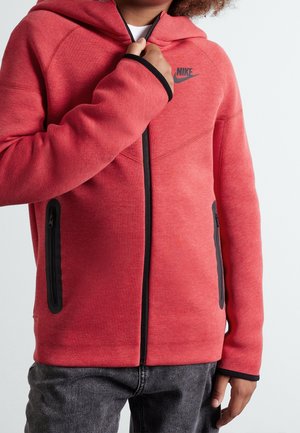 Röd hooded zip-up jacka i mjukt material, med svarta detaljer, två sidfickor med dragkedja och en Nike-logotyp på bröstet.