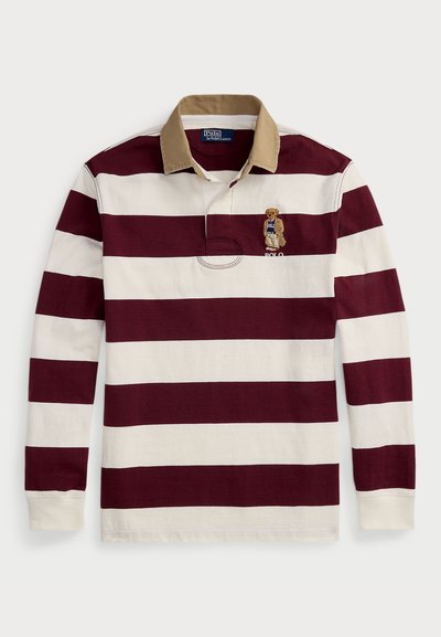 Langermet rugby skjorte med burgunder og kremfargede horisontale striper, en lys brun krage, og en brodert bjørn som bærer en blå "Polo" skjorte.