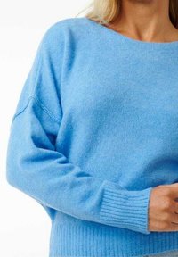 Jasnoniebieski sweter o luźnym kroju, wykonany z miękkiego materiału. Posiada szeroki dekolt, ściągacze przy rękawach oraz teksturowane części ciała dla dodatkowego efektu.