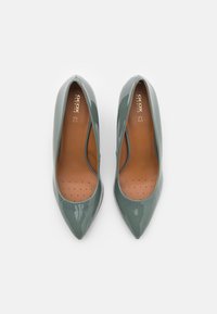 Zielone lakierowane szpilki z wydłużonym czubkiem i niskimi bokami. Brązowa perforowana wkładka z widocznym logo.