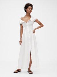 Hvit, av-shoulder maxi kjole med knapplukking foran, korte pufferm og splitt i kanten, laget av lett stoff. Sorte flip-flops.