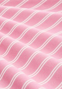 Ροζ ύφασμα με ομοιόμορφα διατεταγμένες, παράλληλες λευκές κυματιστές ρίγες, που δείχνουν απαλές πτυχώσεις και υφή.