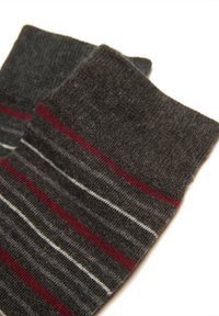 Due calzini grigio scuro con strisce orizzontali in rosso, bianco e grigio più chiaro su uno sfondo bianco.
