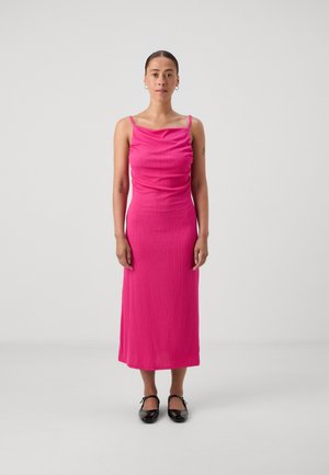Fitted, sleeveless, ribbed dress in bright pink, with a scooped neckline and a midi length, paired with black, block-heeled shoes.