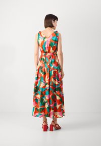 Robe maxi colorée présentant un décolleté en V, sans manches, une taille élastique et un tissu à volants. Motif floral dans des teintes vives de rouge, vert et rose.