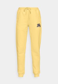 Gelbe Sweatpants aus einer weichen Baumwollmischung, mit einem elastischen Bund und verstellbarem Kordelzug sowie einem kleinen blauen Logo am linken Oberschenkel.