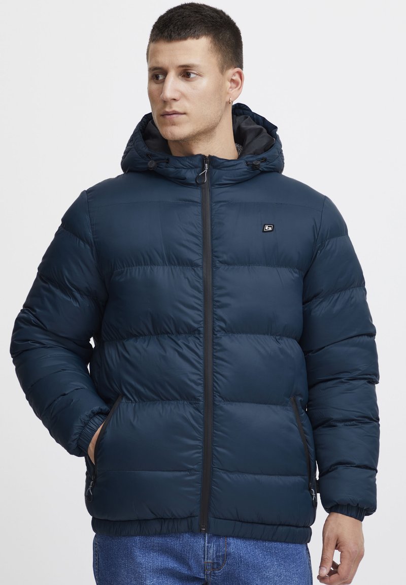 Navy puffer jacket with a zip front, hood, and elastic cuffs. Features quilted design, side pockets, and a small brand logo on chest.