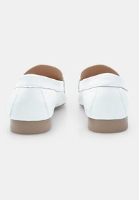 Valkoiset nahka loaferit, joissa on matala beige kumipohja. Pyöreä muoto, jossa on sileä pinta ja huomaamattomat ompeluyksityiskohdat takana.