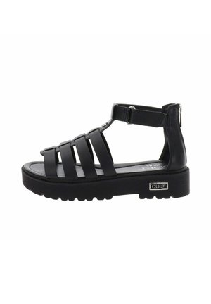 Sandale à plateforme noire avec plusieurs brides horizontales, bride à la cheville avec velcro et semelle épaisse crantée avec logo métallique de la marque sur le côté.