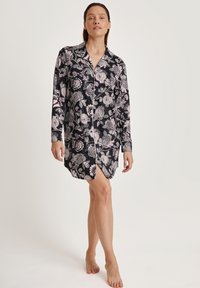 Camicia da notte nera a maniche lunghe con motivi floreali in rosa e bianco, dotata di una chiusura a bottoni sul davanti e un orlo curvo. Tessuto morbido.
