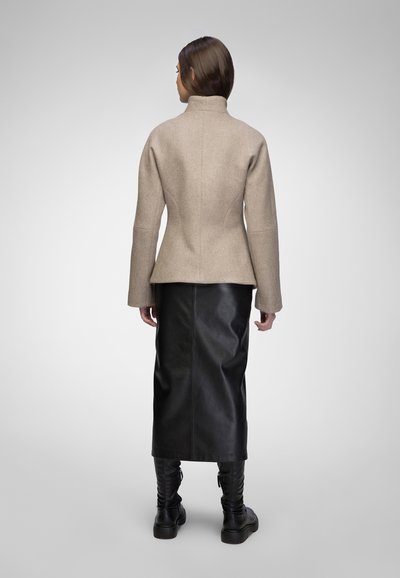 Beige wool blend jacket with a high collar, fitted waist, and long sleeves, paired with a black leather skirt and black knee-high boots.