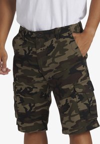 Camouflage cargo shorts in groen en zwart, met een knoopsluiting, zijzakken en een relaxte pasvorm. De stof lijkt duurzaam met een zichtbaar patroon.