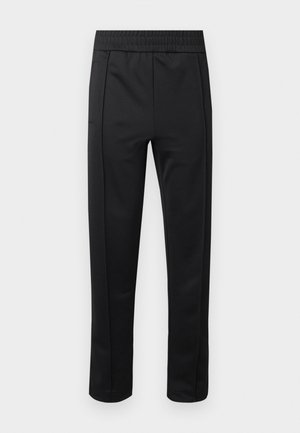 Pantalones negros ajustados con cintura elástica y bolsillos laterales, mostrados sobre un fondo blanco.