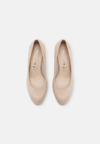 Escarpins en daim beige à talon haut avec un bout rond et une texture lisse. L'intérieur présente le logo de la marque et le gravure de la taille.