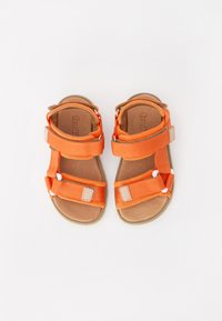 Orange sandaler i mesh och syntetiskt material med två justerbara kardborreband och en brun vadderad sula. Platt sula.