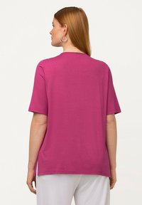 T-shirt magenta a maniche corte con collo a giro, texture morbida e spacchi laterali all'orlo per una maggiore libertà di movimento.