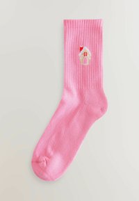 Sosete roz cu dungi, cu o mică broderie în formă de casă de turtă dulce, având detalii roșii, albe și bej în apropierea manșetei.
