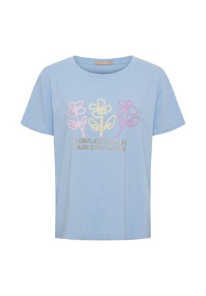 Lyseblå kortærmet skjorte med tre pastelfarvede broderede blomster og guldtekst med teksten "FRA STED TIL STED NYD ALLE STEDER."