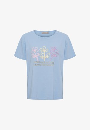 Lyseblå kortærmet skjorte med tre pastelfarvede broderede blomster og guldtekst med teksten "FRA STED TIL STED NYD ALLE STEDER."