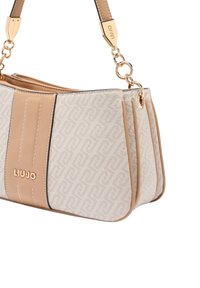 Bolso beige y blanco con un patrón texturizado, herrajes dorados y una base de cuero suave. Presenta una forma estructurada y una correa ajustable.
